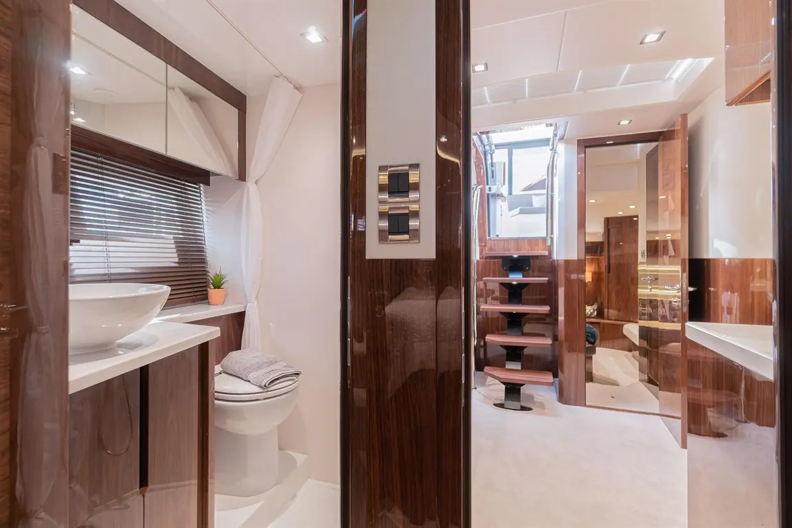 Luxurious yacht interior featuring a modern bathroom with a basin, toilet, and steps leading to an elegant living area.
